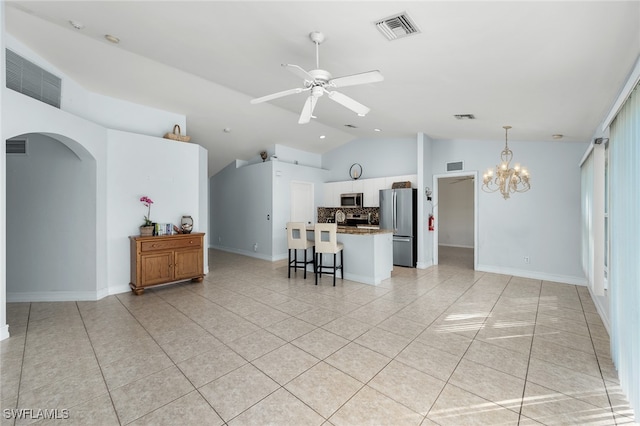 kitchen with appliances with stainless steel finishes, ceiling fan with notable chandelier, a kitchen breakfast bar, lofted ceiling, and light tile patterned floors