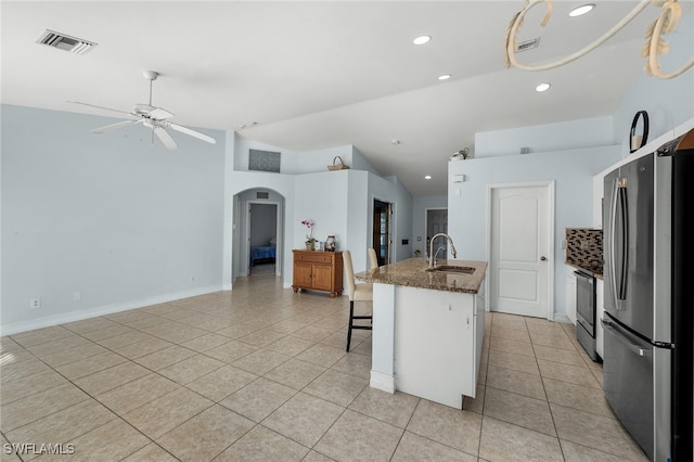 kitchen featuring appliances with stainless steel finishes, light tile patterned flooring, sink, white cabinets, and a breakfast bar area