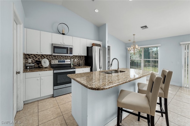 kitchen with lofted ceiling, sink, white cabinets, decorative light fixtures, and appliances with stainless steel finishes