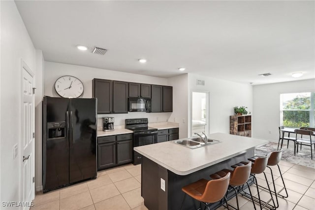 kitchen with light tile patterned floors, light countertops, visible vents, a sink, and black appliances