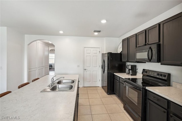 kitchen with light tile patterned floors, light countertops, visible vents, a sink, and black appliances