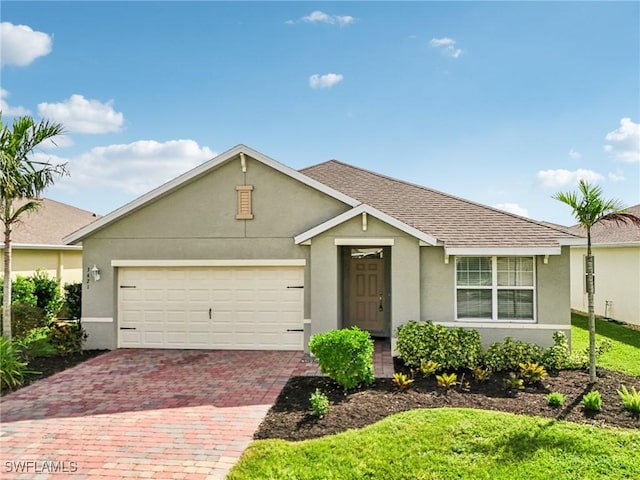 single story home featuring a garage, decorative driveway, a shingled roof, and stucco siding