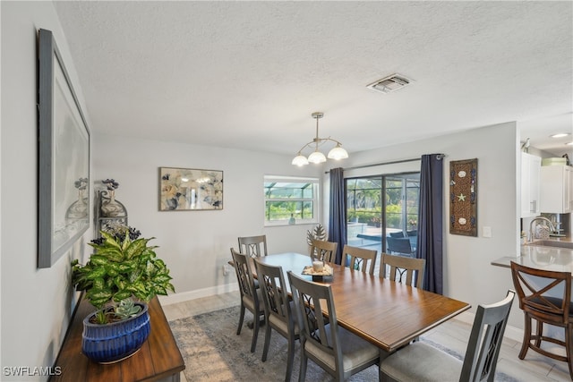 dining space with hardwood / wood-style flooring, a textured ceiling, sink, and a chandelier