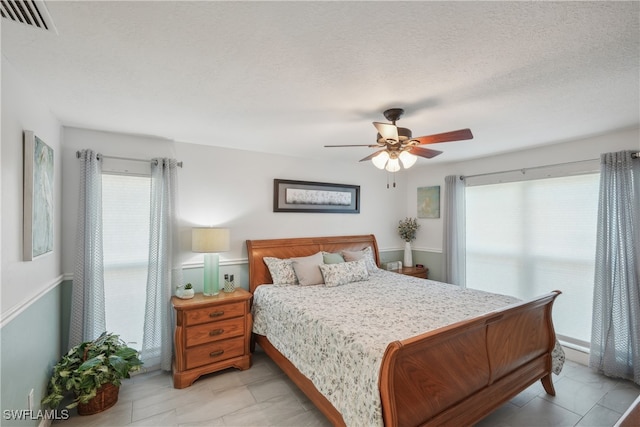 bedroom with ceiling fan and a textured ceiling