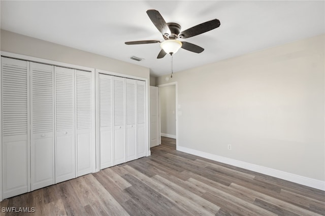 unfurnished bedroom with ceiling fan, multiple closets, and light hardwood / wood-style flooring