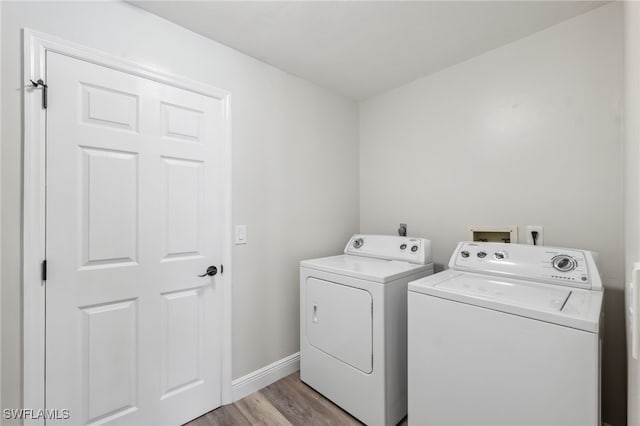 clothes washing area featuring washing machine and clothes dryer and light hardwood / wood-style flooring