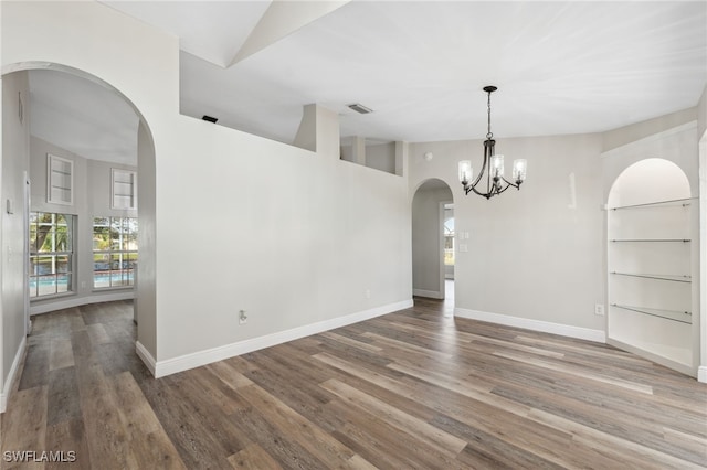 unfurnished dining area with an inviting chandelier, a high ceiling, and hardwood / wood-style flooring