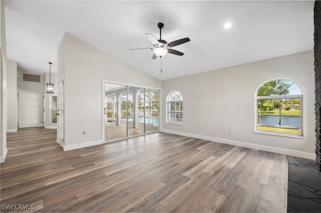 empty room with wood-type flooring, vaulted ceiling, ceiling fan, and a healthy amount of sunlight