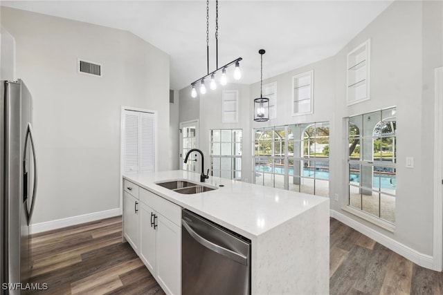 kitchen with appliances with stainless steel finishes, dark hardwood / wood-style flooring, decorative light fixtures, white cabinetry, and an island with sink