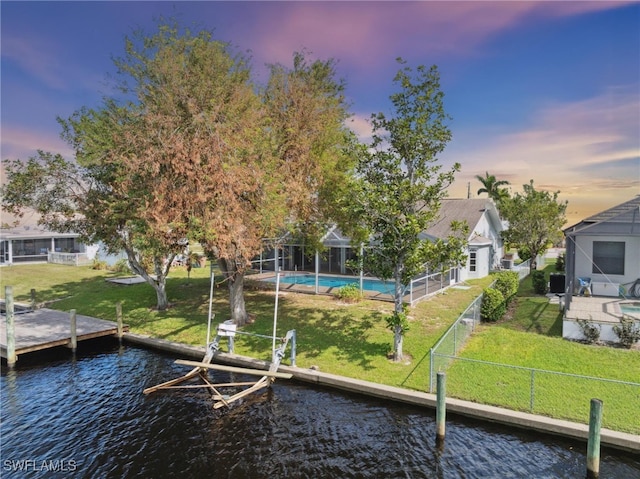 dock area with a lanai, a water view, and a yard