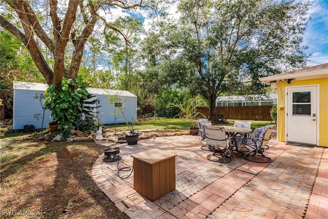 view of patio / terrace featuring a storage shed and an outdoor fire pit