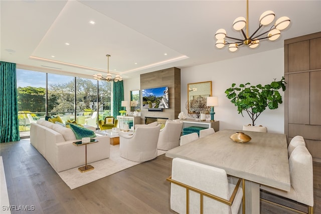 living room with a notable chandelier, hardwood / wood-style flooring, and a raised ceiling