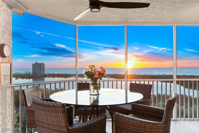 sunroom with a water view and ceiling fan