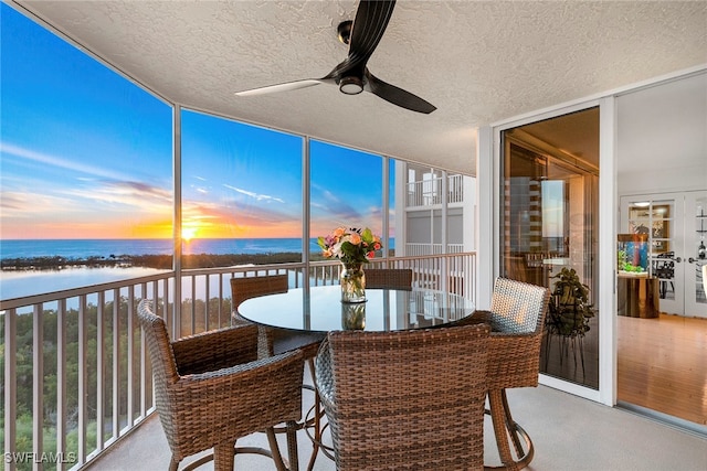 sunroom with a water view and ceiling fan