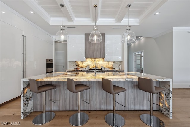 kitchen with a kitchen breakfast bar, white cabinets, hanging light fixtures, and a large island