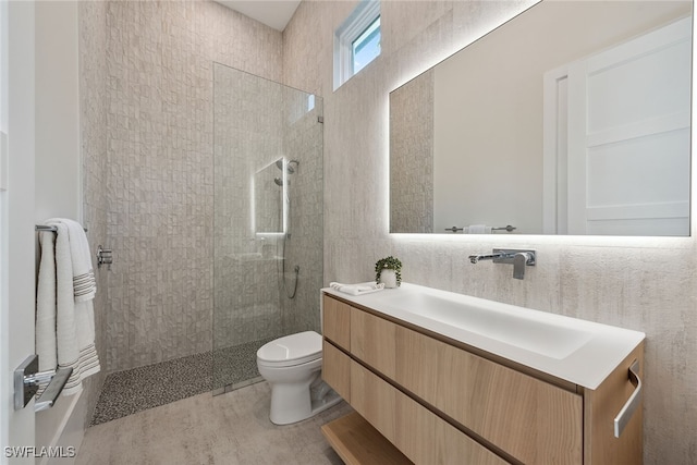 bathroom featuring vanity, toilet, tiled shower, and tile patterned flooring