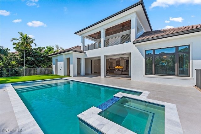 rear view of house with a balcony, a lawn, a patio, and a pool with hot tub