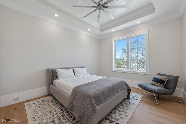 bedroom with ornamental molding, a raised ceiling, light wood-type flooring, and ceiling fan