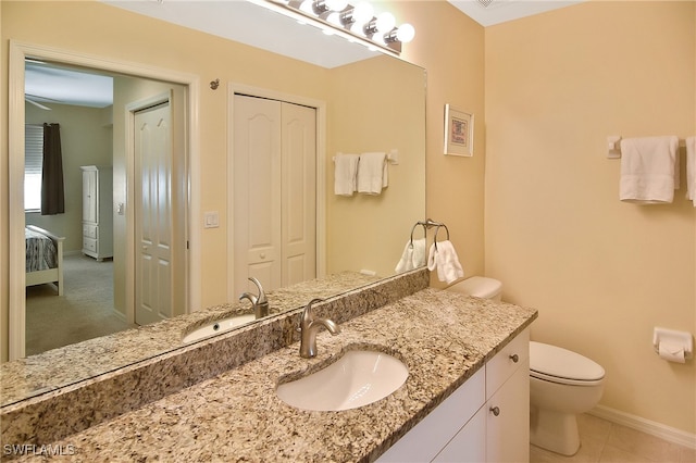 bathroom with toilet, vanity, and tile patterned flooring