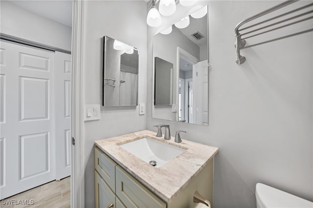 bathroom with vanity, toilet, and hardwood / wood-style floors