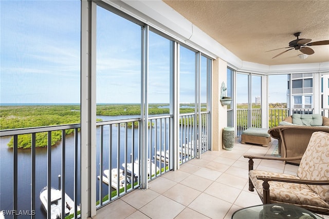 sunroom / solarium featuring a water view and ceiling fan