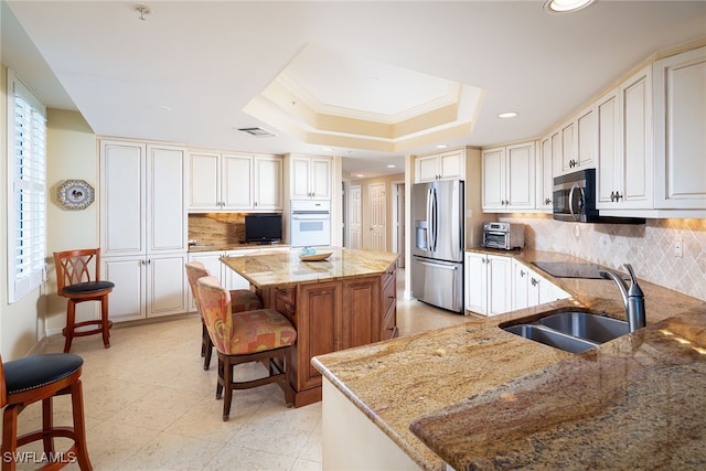 kitchen with light stone countertops, appliances with stainless steel finishes, sink, a center island, and a kitchen breakfast bar