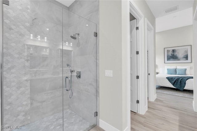 bathroom with a marble finish shower, wood finished floors, and ensuite bathroom