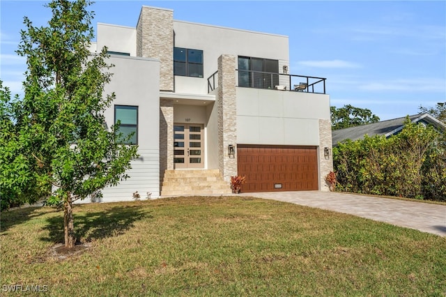 modern home featuring stucco siding, a front yard, a balcony, stone siding, and driveway