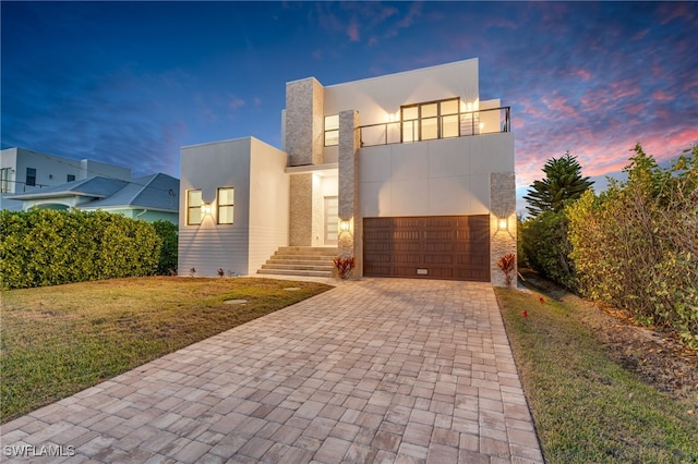 contemporary home featuring a balcony, a garage, and a lawn