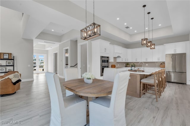 dining room featuring visible vents, baseboards, a raised ceiling, light wood-style floors, and recessed lighting