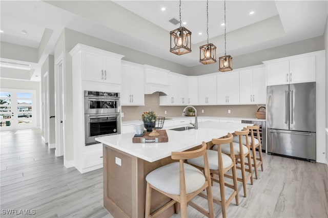 kitchen featuring tasteful backsplash, visible vents, appliances with stainless steel finishes, a kitchen island with sink, and a sink