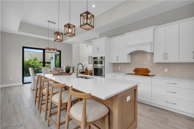 kitchen featuring double oven, black electric stovetop, decorative backsplash, and a sink