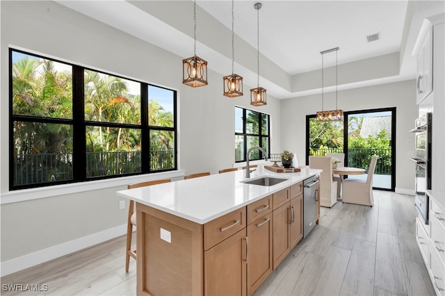 kitchen with a sink, visible vents, light countertops, appliances with stainless steel finishes, and hanging light fixtures