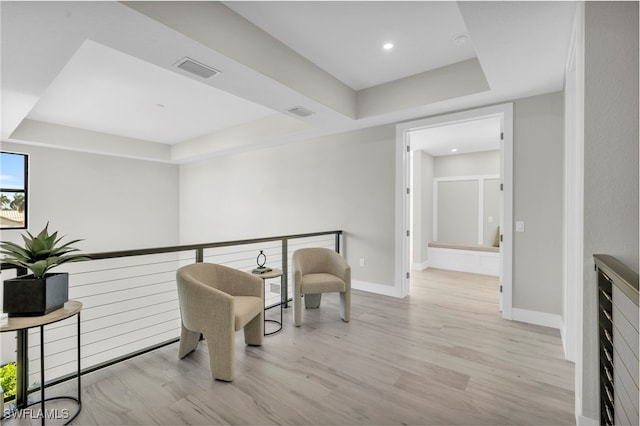 sitting room featuring a raised ceiling, visible vents, baseboards, and wood finished floors