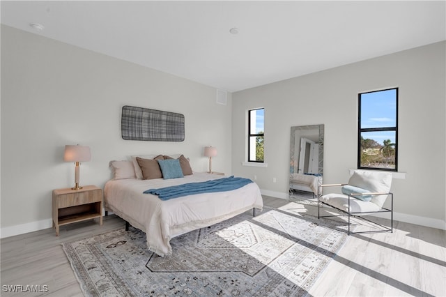 bedroom with light wood-style floors, visible vents, and baseboards