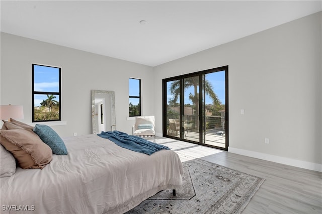 bedroom with access to outside, wood finished floors, and baseboards