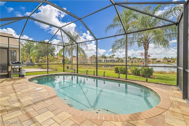 view of swimming pool with area for grilling, a water view, a lawn, a patio, and glass enclosure