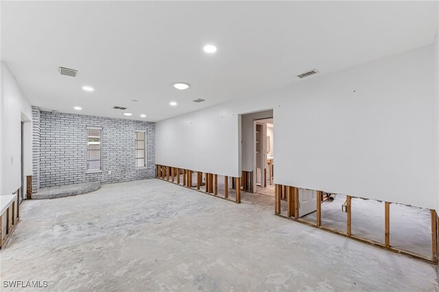 empty room with concrete floors and brick wall