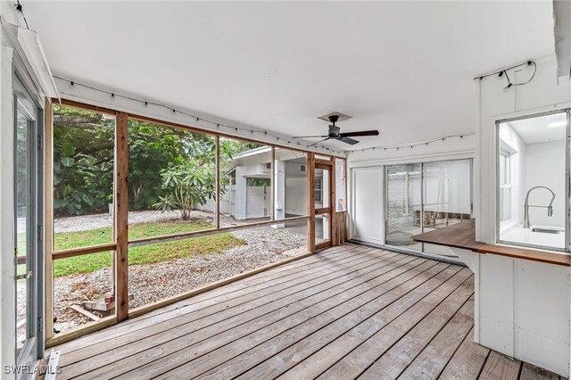 unfurnished sunroom with ceiling fan