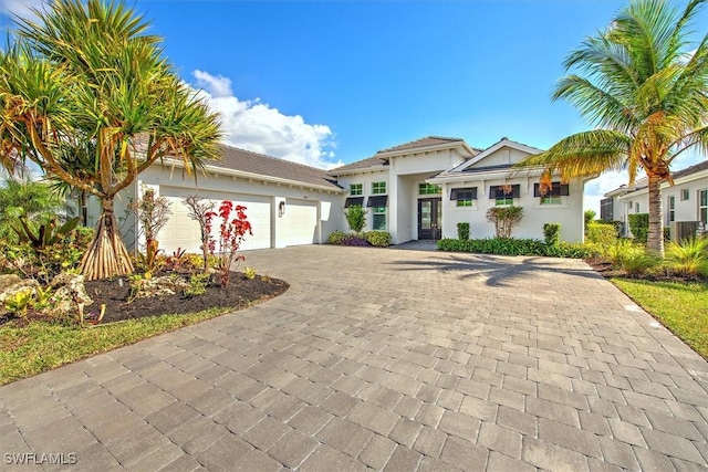 view of front facade with decorative driveway, a garage, and stucco siding