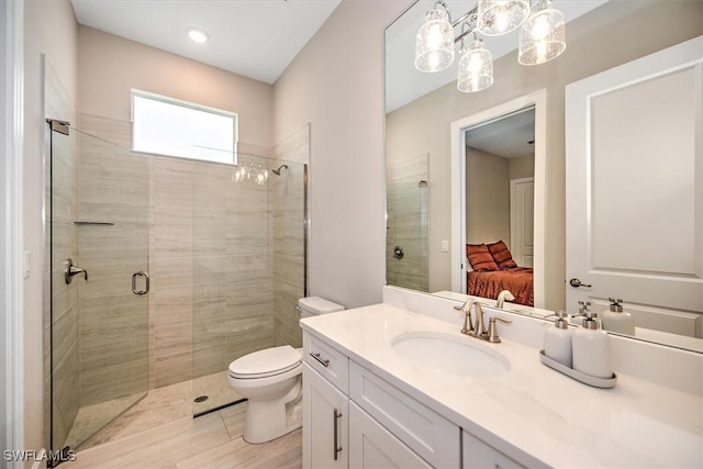 bathroom featuring a shower with door, toilet, and vanity