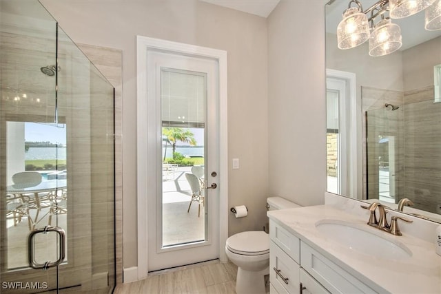 bathroom featuring a shower with door, toilet, and vanity