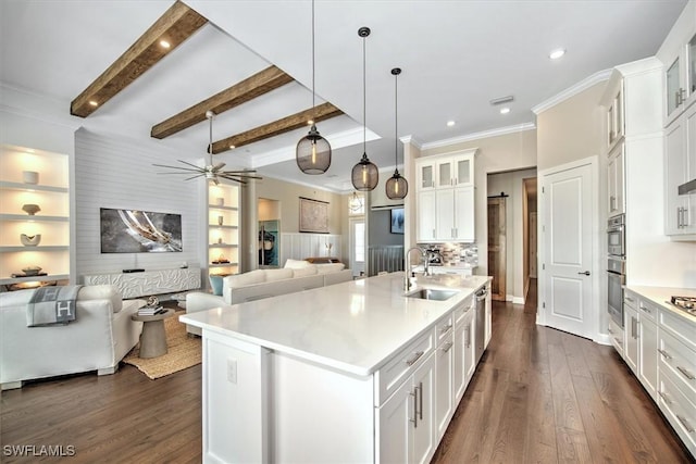 kitchen with beam ceiling, dark wood-type flooring, a sink, open floor plan, and white cabinetry