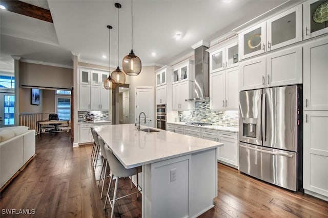 kitchen featuring white cabinetry, stainless steel appliances, wall chimney exhaust hood, and a kitchen island with sink