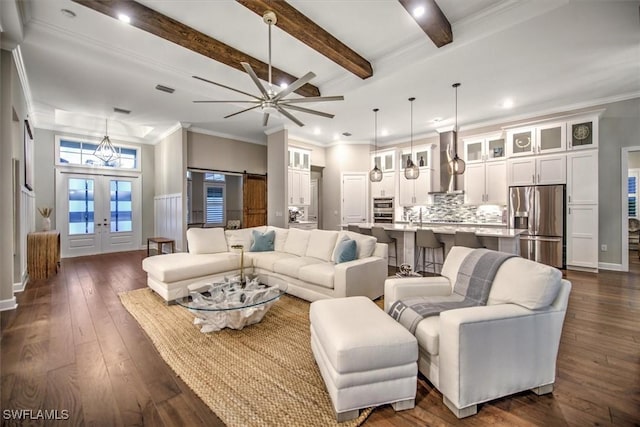 living room with ceiling fan, french doors, dark wood-type flooring, beam ceiling, and a barn door