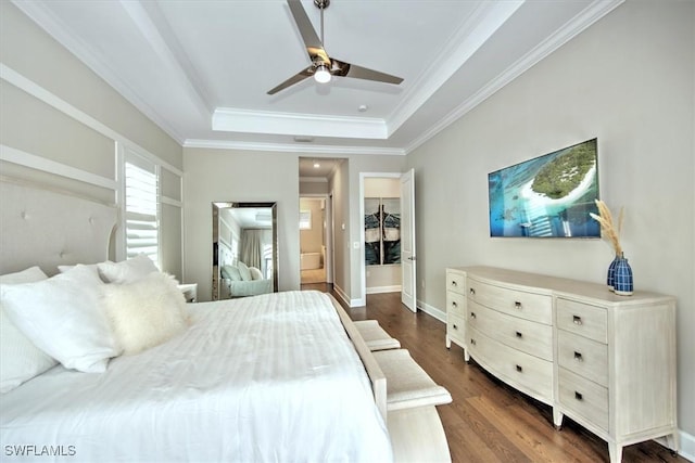 bedroom featuring ensuite bath, ornamental molding, dark hardwood / wood-style flooring, ceiling fan, and a tray ceiling