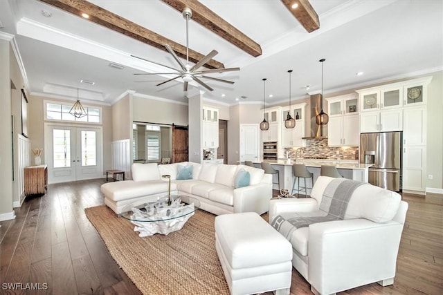 living room with dark hardwood / wood-style flooring, french doors, ornamental molding, beam ceiling, and a barn door