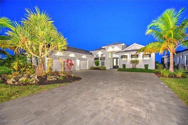 view of front of home featuring stucco siding, decorative driveway, and a garage