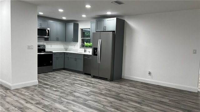 kitchen featuring light hardwood / wood-style floors, appliances with stainless steel finishes, sink, and gray cabinets