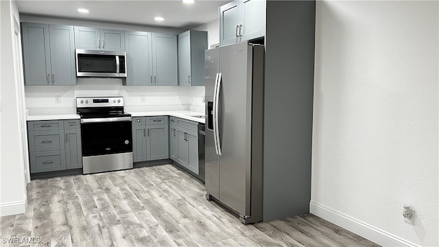 kitchen featuring gray cabinetry, appliances with stainless steel finishes, and light wood-type flooring